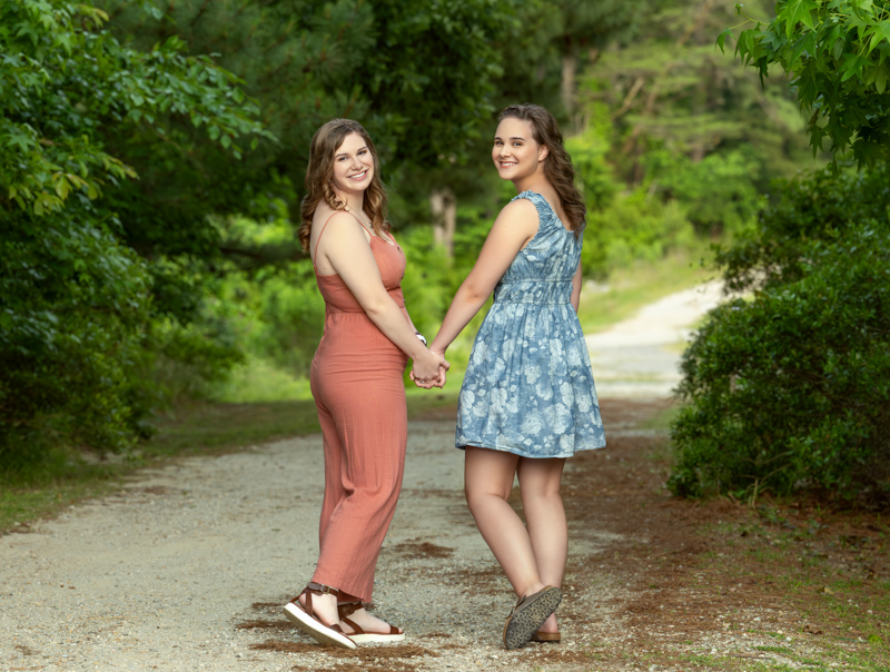 A portrait of two sisters in the park holding hands, taken by Marika H Photography in Williamsburg, VA