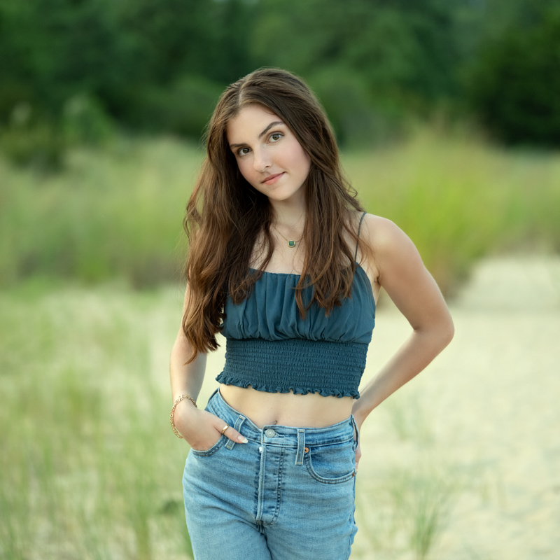 High school senior photo of a girl standing on a grassy beach in Williamsburg, VA, taken by Marika H Photography